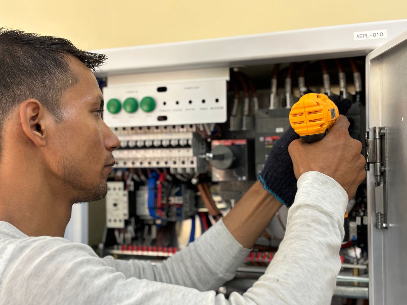 Electrician securing a breaker panel with a drill